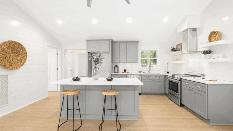 Modern farmhouse-style kitchen renovation in Hudson Valley featuring soft gray cabinets, quartz countertops, under-cabinet lighting, and center island seating.