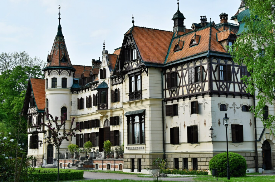 Elegant historic European villa with ornate architecture, steep tiled roofs, timber framing, and landscaped gardens.