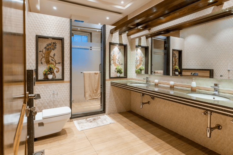 Luxury bathroom with double sink vanity, large wall mirrors, glass shower enclosure, and warm ambient lighting.