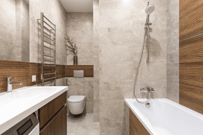 Modern bathroom with bathtub and shower combo, wood-accent wall panels, floating vanity, and large neutral stone tiles.