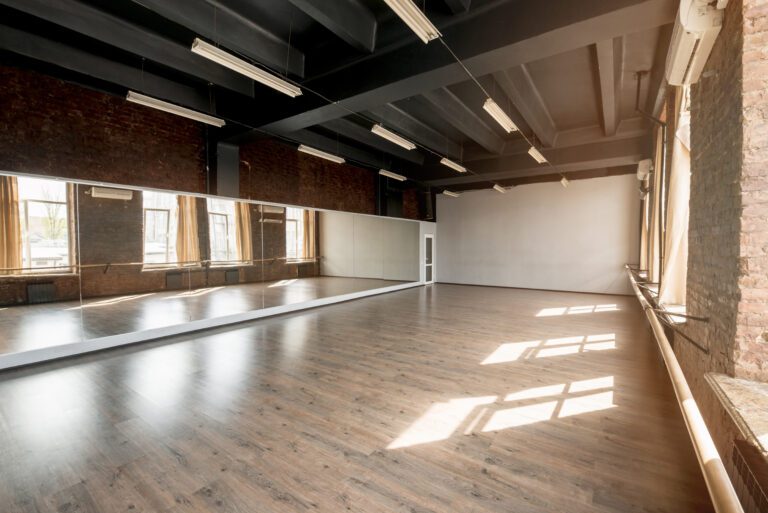 Finished basement home gym with open layout, wood flooring, mirrors, and natural light, ideal for Hudson Valley families.